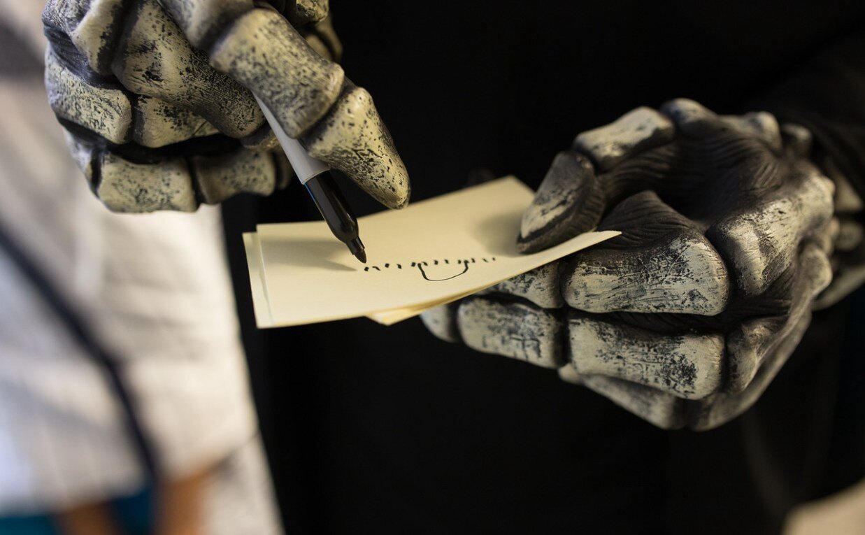 Skeletal hands writing on an index card with a marker