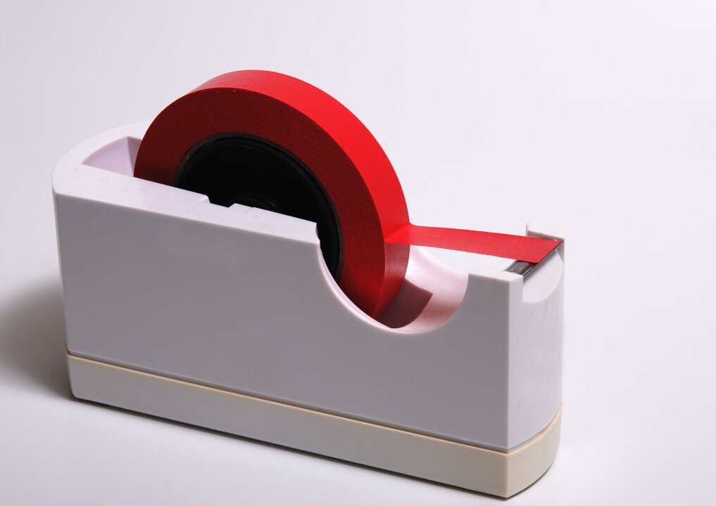 A roll of red tape in a desktop dispenser
