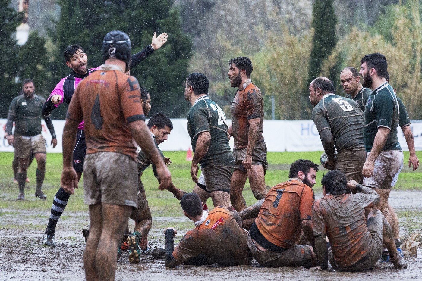 Rugby players scrambling in the mud during a rainy match