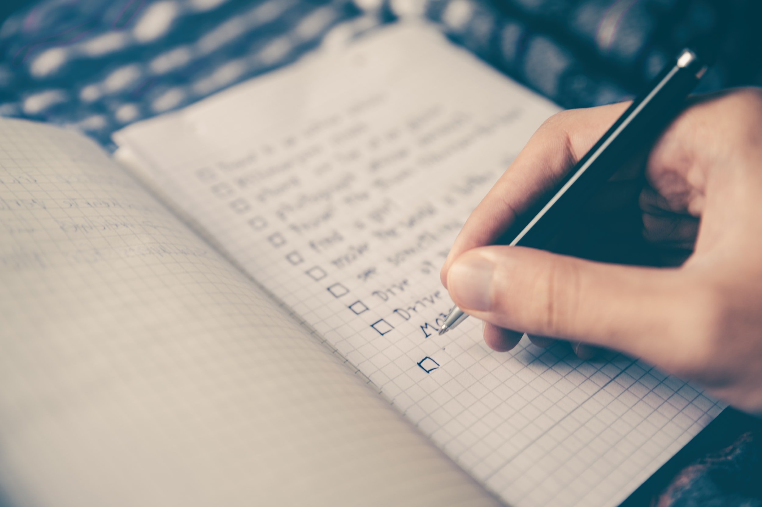 A hand writing a checklist in a notebook