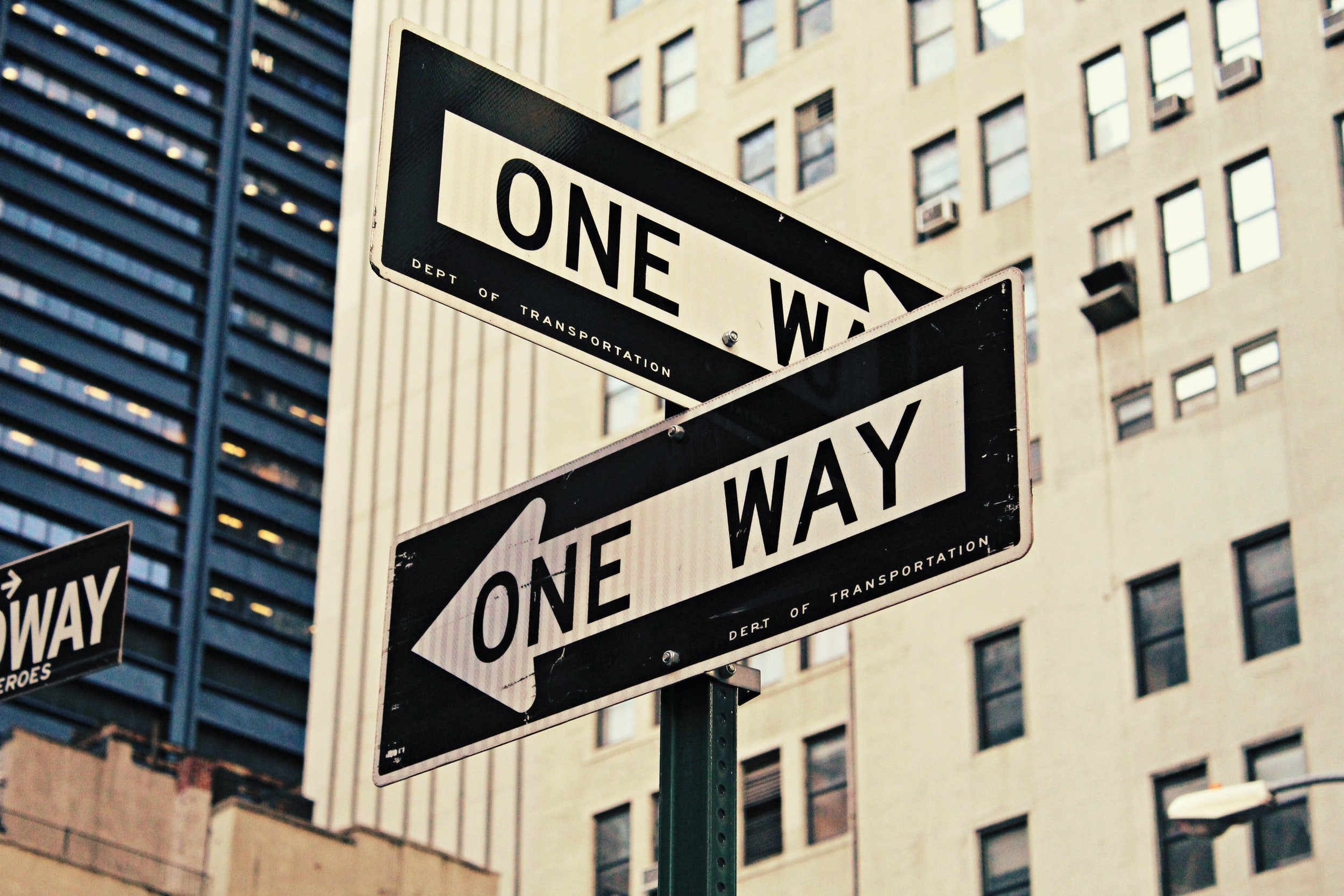 Two &ldquo;One Way&rdquo; street signs mounted on the same pole pointing in opposite directions