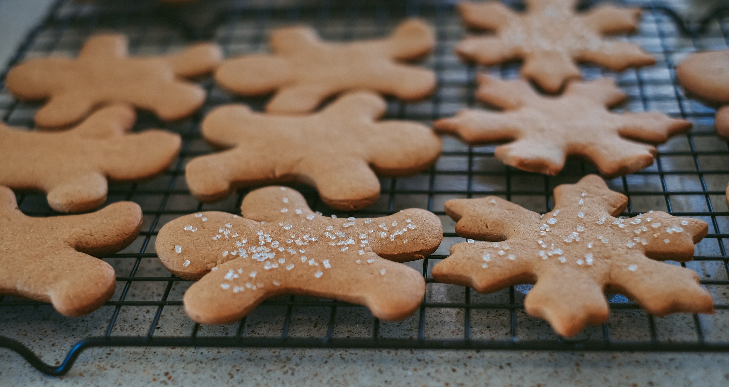 Gingerbread cookies in people and snowflake shapes cooling on a rack